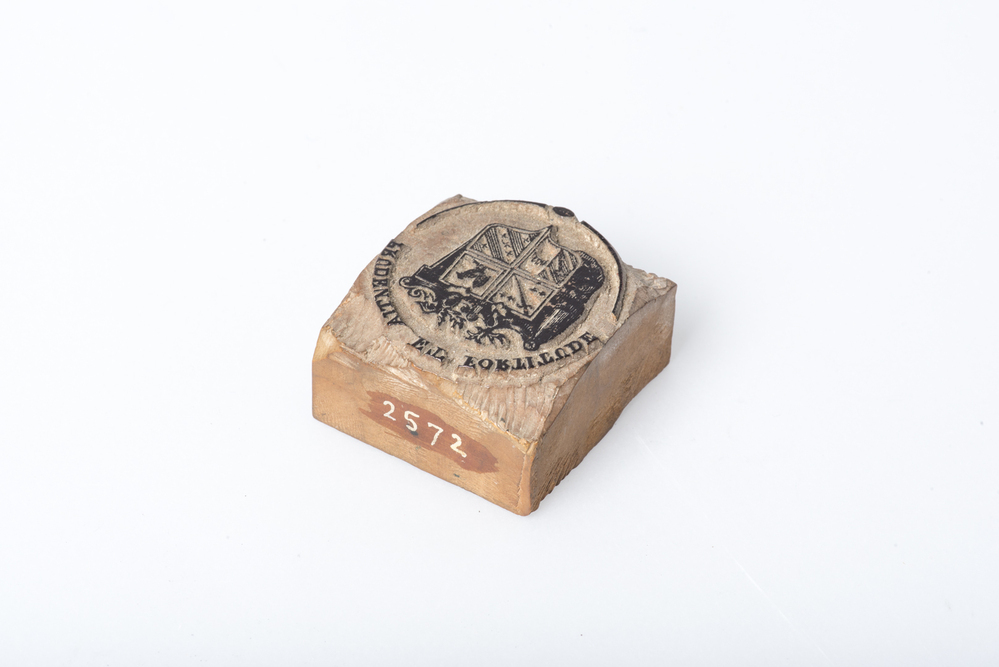 Palmhouten blokje, waarop is uitgesneden een familiewapen