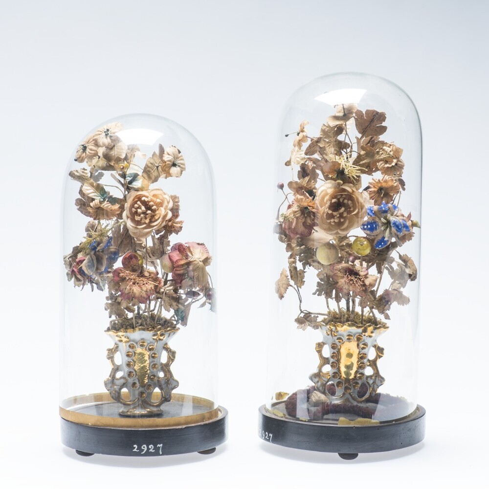 Twee vazen met kunstbloemen onder glas