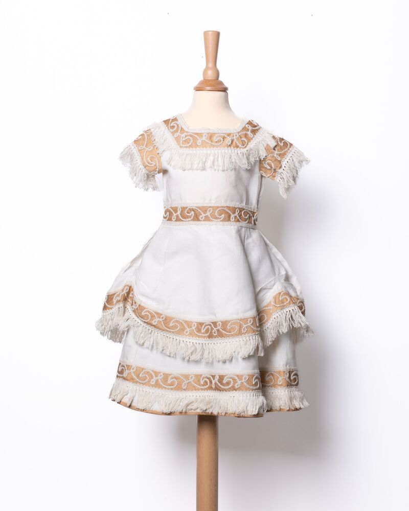 Kinderjurkje van wit (crème) piqué met grote, losse strik