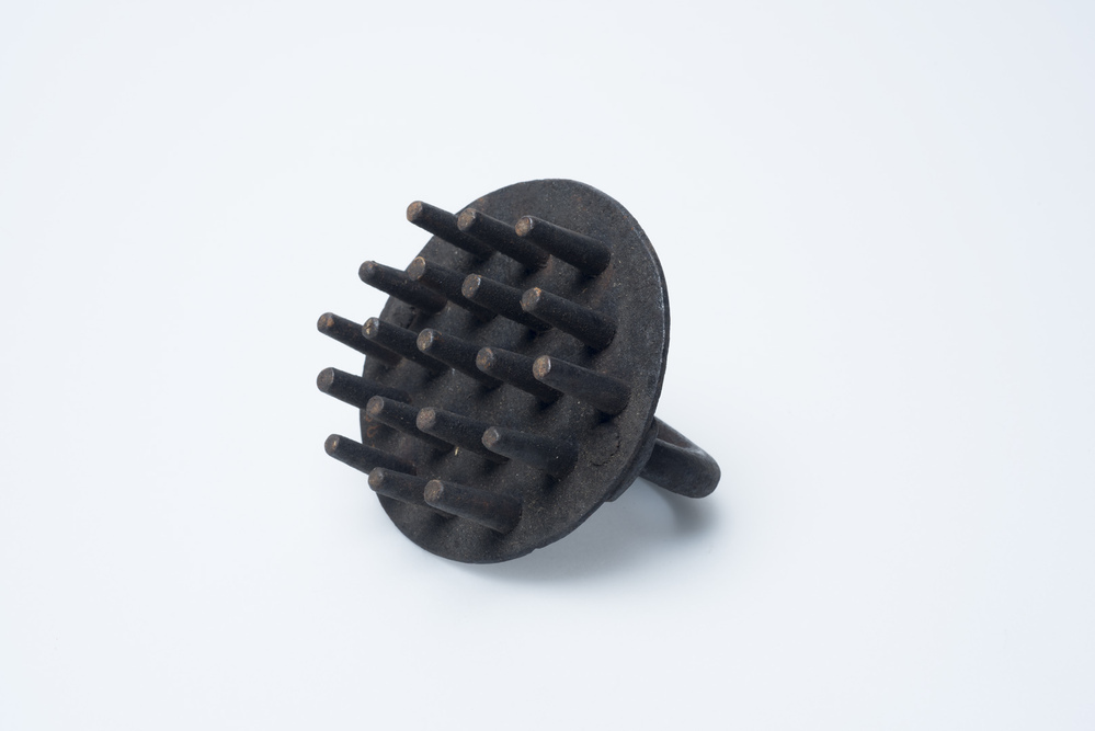 Plaat met dikke ijzeren pennen om gaten in hardbroden te maken