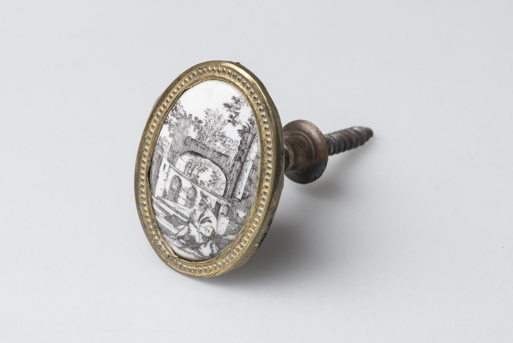 Deurknop van geëmailleerd koper gevat in smalle
koperen rand