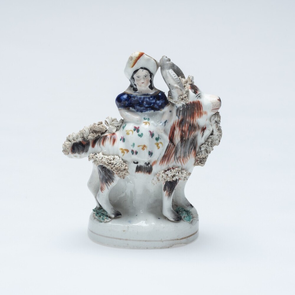 Beeldje van een meisje op een bok zittend