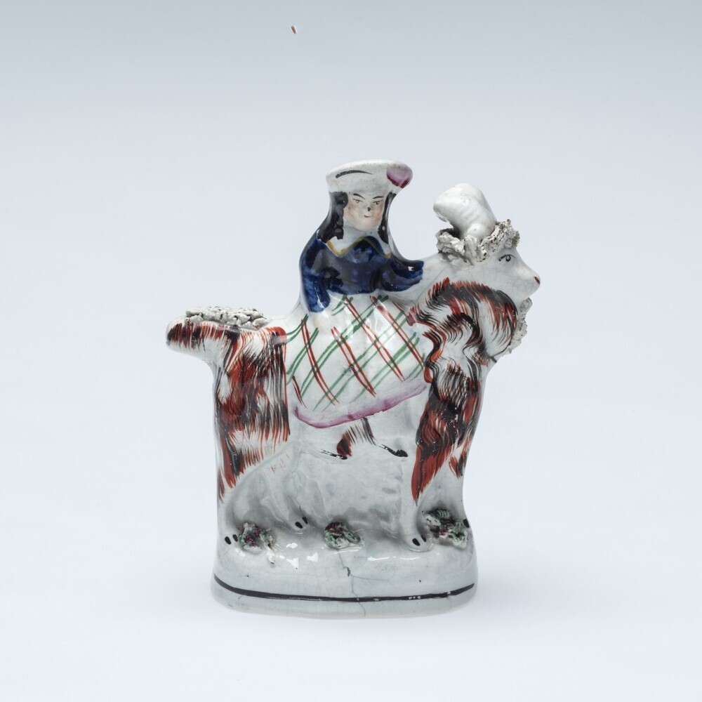 Beeldje van een meisje op een bok zittend