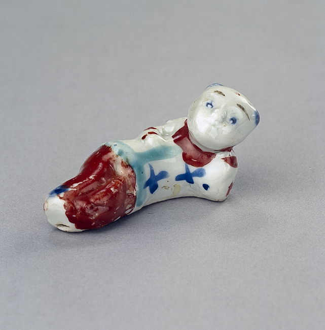 Fluitje in de vorm van een achterover leunend jongetje