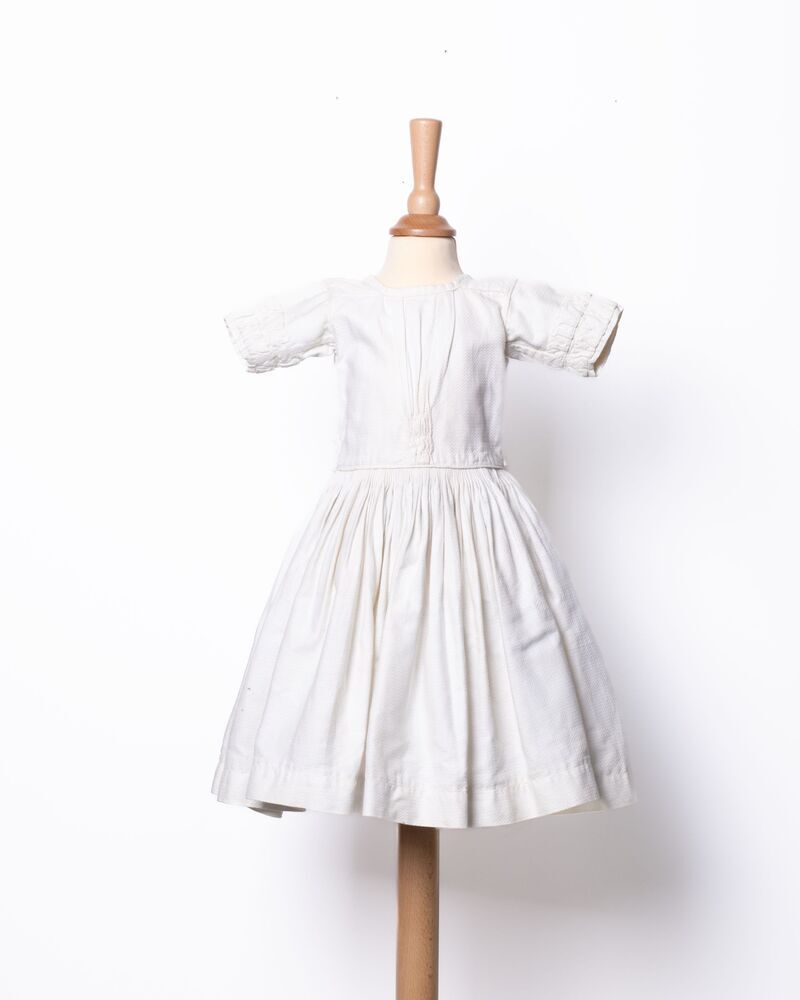 Kinderjurkje van wit katoen en zigzagmotieven