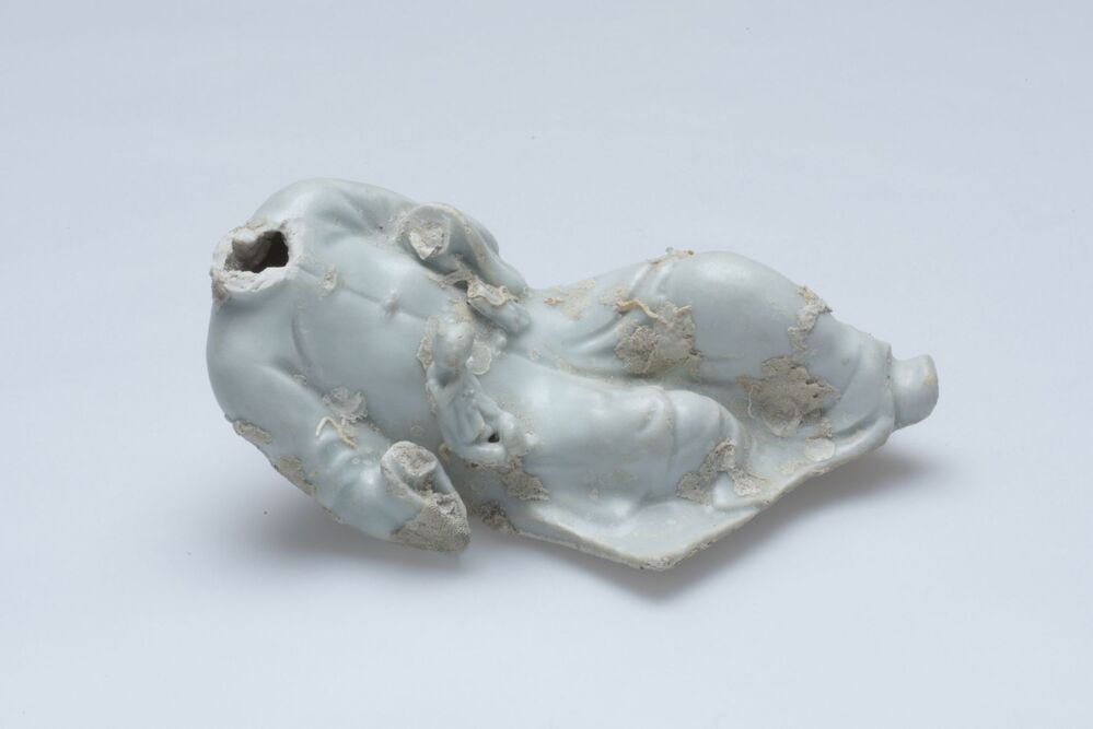 Beeldje van een liggende figuur met een kind op de zij