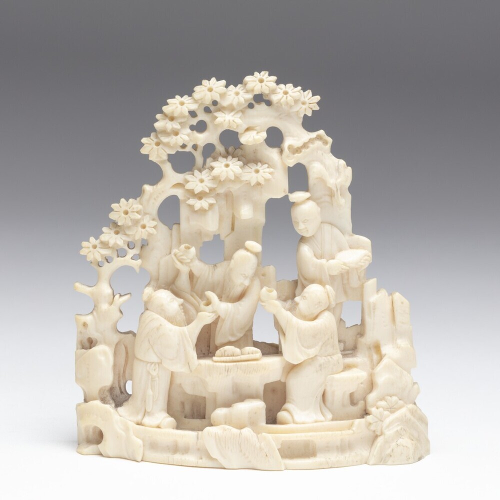 Beeldengroep van figuren aan een maaltijd bij rotspartij,