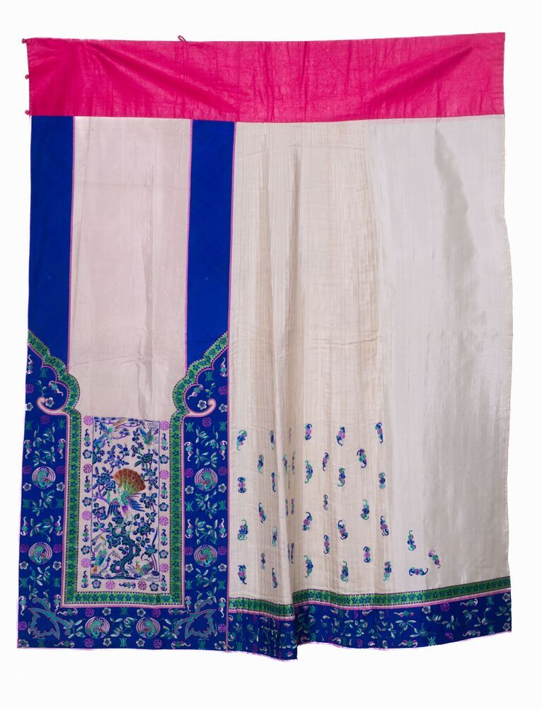 Een crème zijden schort(?) met blauwe banen en borduursel