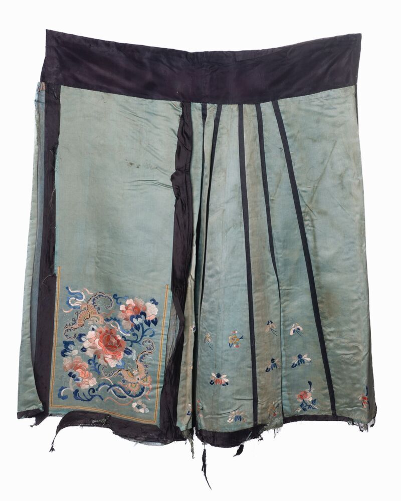 Een groen zijden schort (?) met zwarte banden en geborduurde bloemmotieven